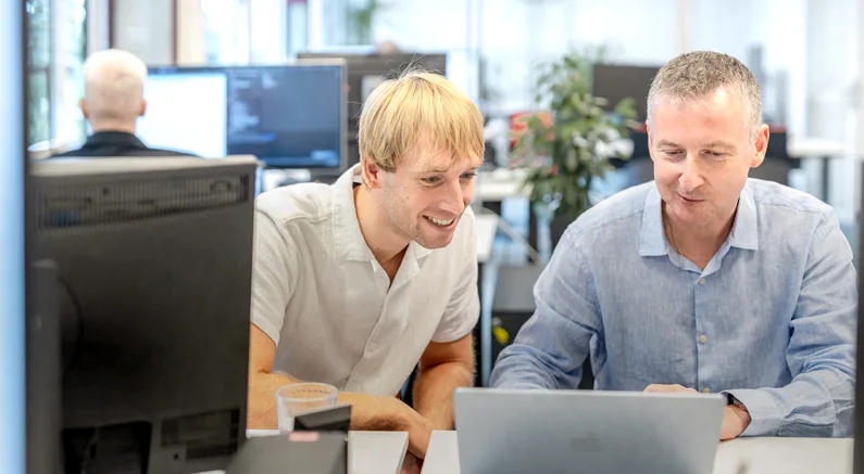 Zwei Mitarbeiter von Datalizard schauen auf einen Laptop.